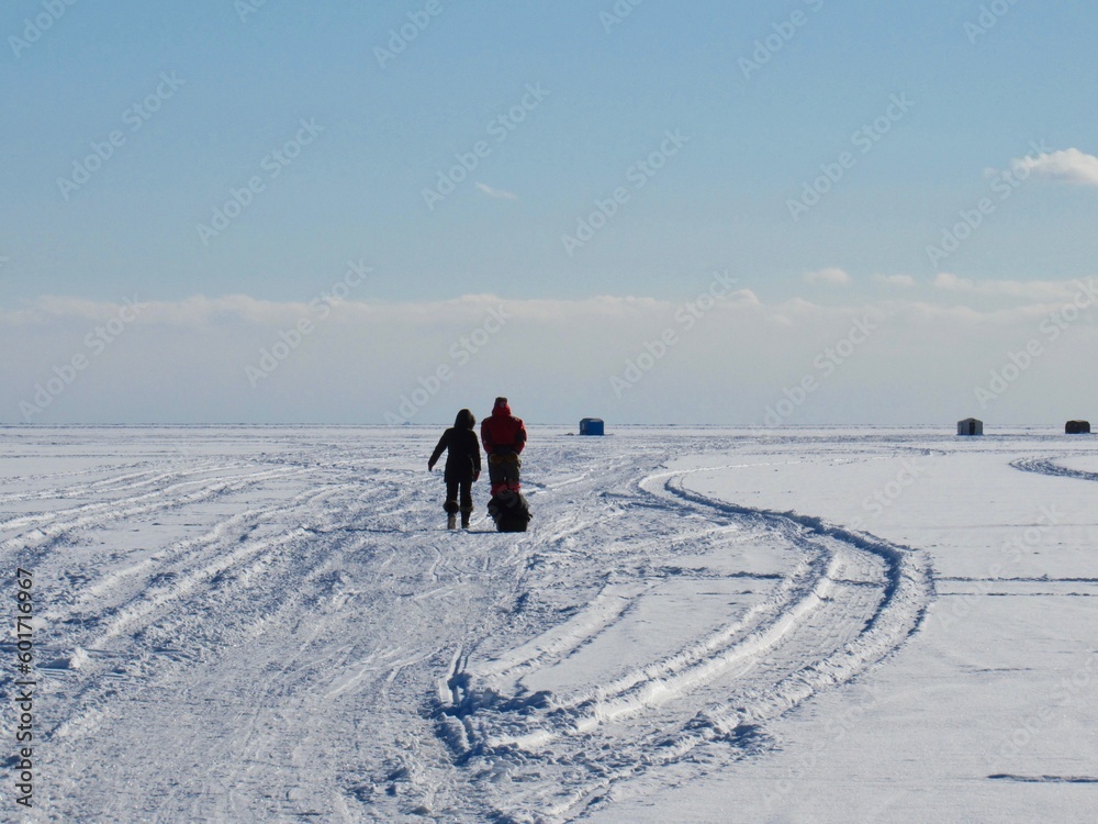 People walking on frozen Lake Simcoe to their ice fishing hut