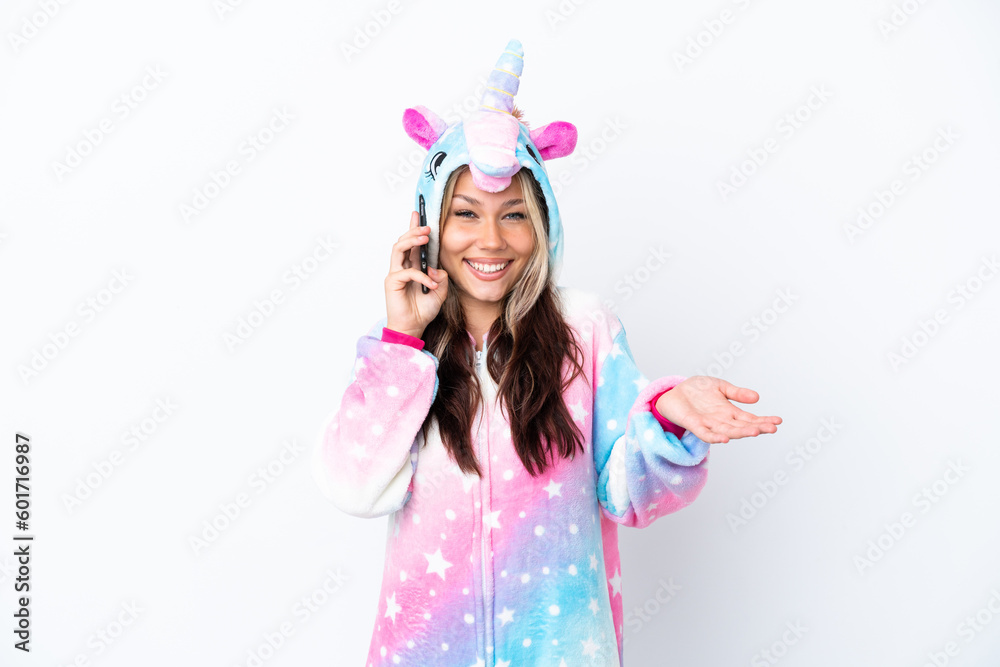 Young Russian woman wearing a unicorn pajama isolated on white background keeping a conversation with the mobile phone with someone Young Russian woman wearing a unicorn pajama isolated on white background keeping a conversation with the mobile phone with someone