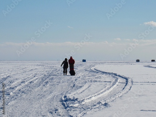 People walking on frozen Lake Simcoe to their ice fishing hut