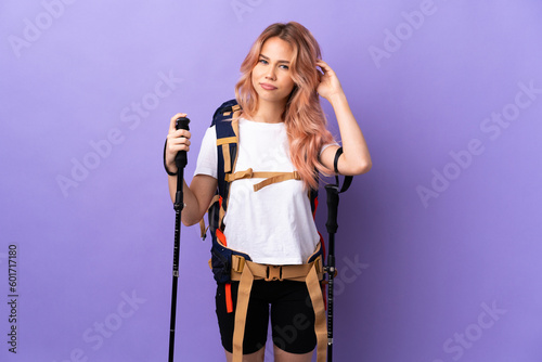 Teenager girl with backpack and trekking poles over isolated purple background having doubts