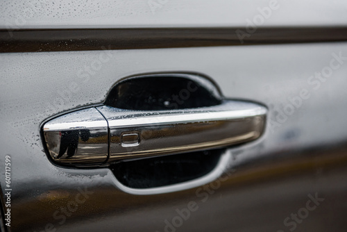 Car door handle with keyless go sensor. Touch sensor for door opening. Automatic opening of a car door without a key. The exterior design of a new black luxury car. Closeup. © Serhii