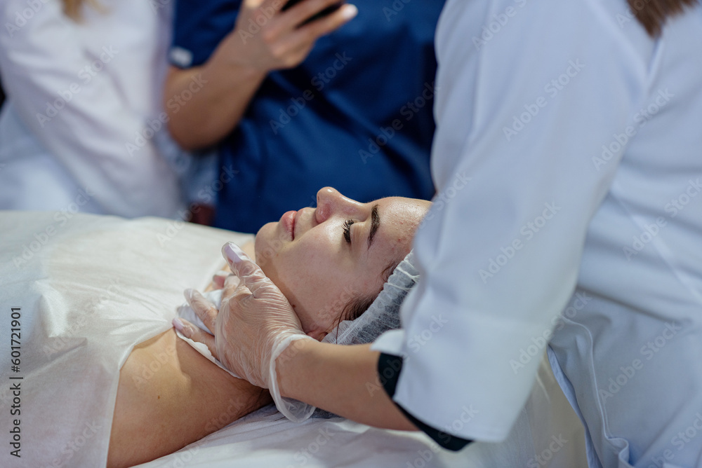 A pretty young girl in a disposable hat is lying on the couch, face close-up. Training of cosmetologists in skin care, preparation for the procedure and pilling A pretty young girl in a disposable hat is lying on the couch, face close-up. Training of cosmetologists in skin care, preparation for the procedure and pilling