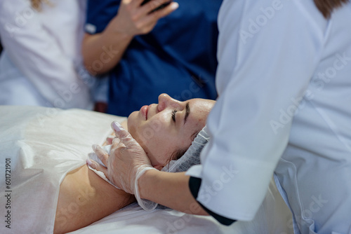 A pretty young girl in a disposable hat is lying on the couch  face close-up. Training of cosmetologists in skin care  preparation for the procedure and pilling