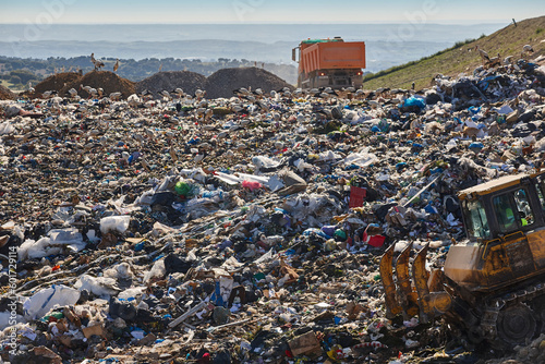 Heavy machinery shredding garbage in an open air landfill. Pollution