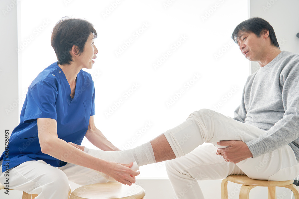 Obraz premium 足首に包帯を巻く看護師