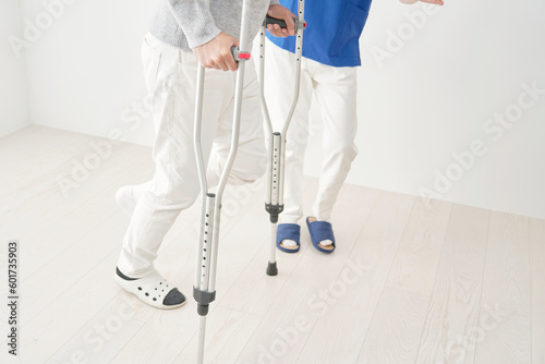 松葉杖を使って歩くリハビリをする中年男性　顔無し