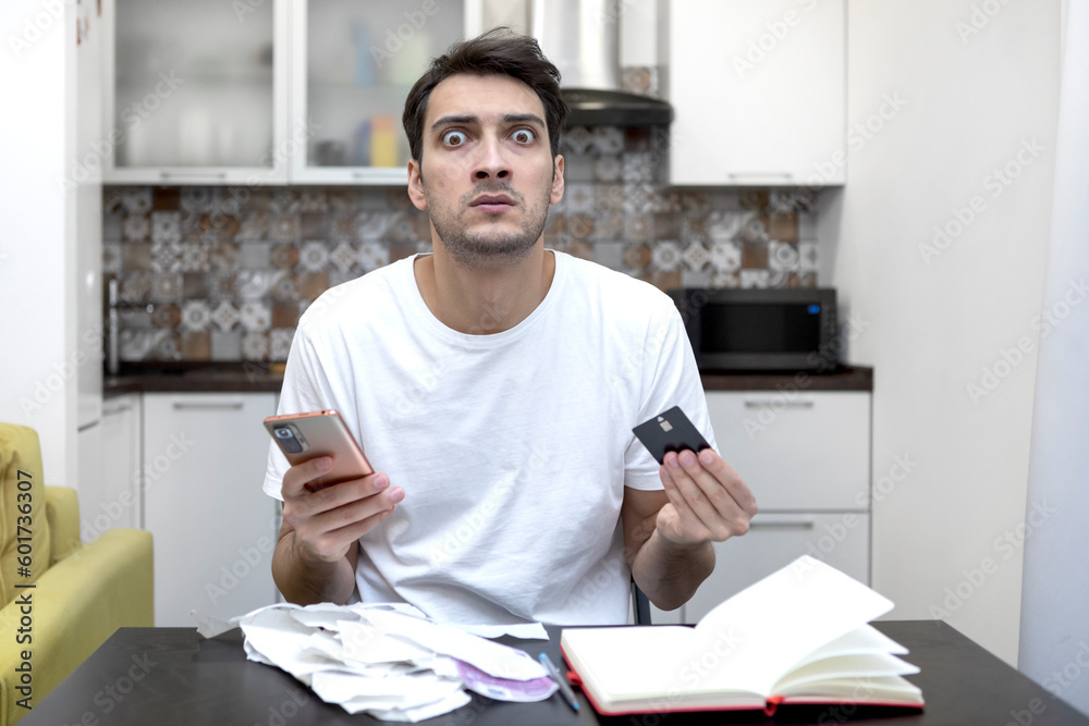 Close up of unhappy man sitting at the table, stressed and confused by calculate expense from invoice or bills, have no money to pay mortgage or loan. High prices and spending money concept Close up of unhappy man sitting at the table, stressed and confused by calculate expense from invoice or bills, have no money to pay mortgage or loan. High prices and spending money concept
