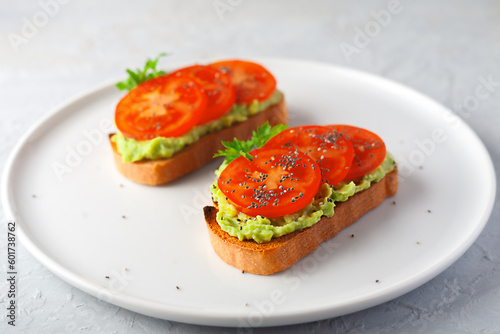 Vegan sandwich with avocado and tomatoes on a white dish