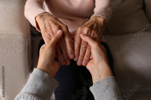 Cropped shot of elderly woman and female geriatric social worker holding hands. Women of different age comforting each other. Close up, background, copy space.
