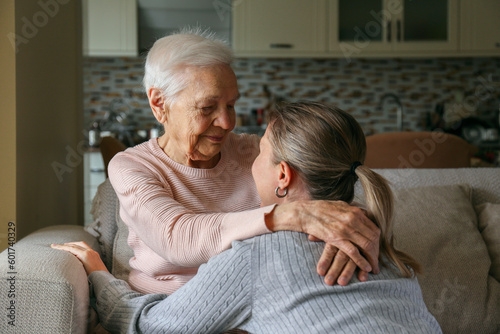Grandmother and granddaughter hugging in the living room. Two adult women of different age. Family values concept. Close up, copy space, background.