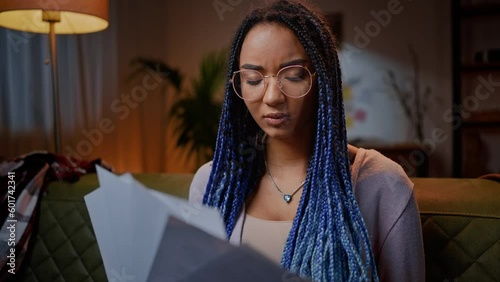 Close-up portrait of a perplexed pensive African young woman working on a magazine article at home photo