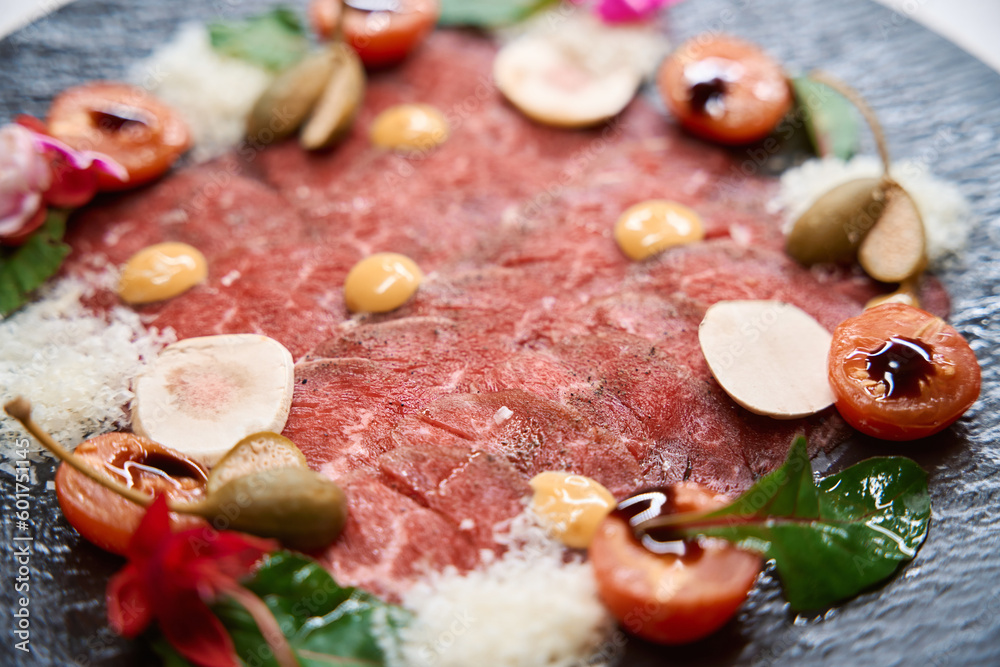 Cold appetizer beef carpaccio on black plate Cold appetizer beef carpaccio on black plate