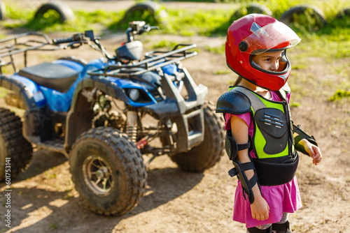 The little girl in protective clothing. Electric quad bike electric car for children popularizes green technology.