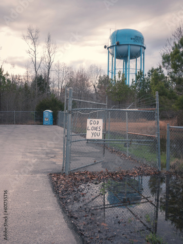 God loves you sign with port-a-potty and water tower