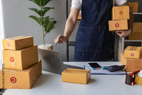 Small business entrepreneurs, SMEs, freelancers, working with boxes at home, using laptops for commercial inspection. Online Marketing SME Packaging Box Shipping Concept © MrAshi