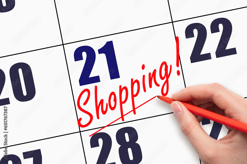 21st day of the month. Hand writing text SHOPPING and drawing a line on calendar date. 21st day of the month. Hand writing text SHOPPING and drawing a line on calendar date.
