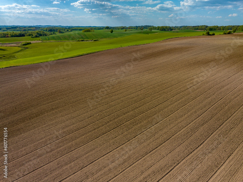 Fototapeta Naklejka Na Ścianę i Meble -  Aerial view of plowed agricultural field in spring with blue sky, Poland, Mazury