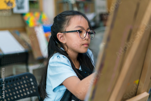 Young girl asian sitting and painting watercolour artwork to develop abilities and improve mental health at home .Female artist drawing with inspiration.