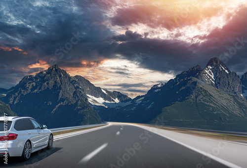 A white travel car drives along a mountain road.