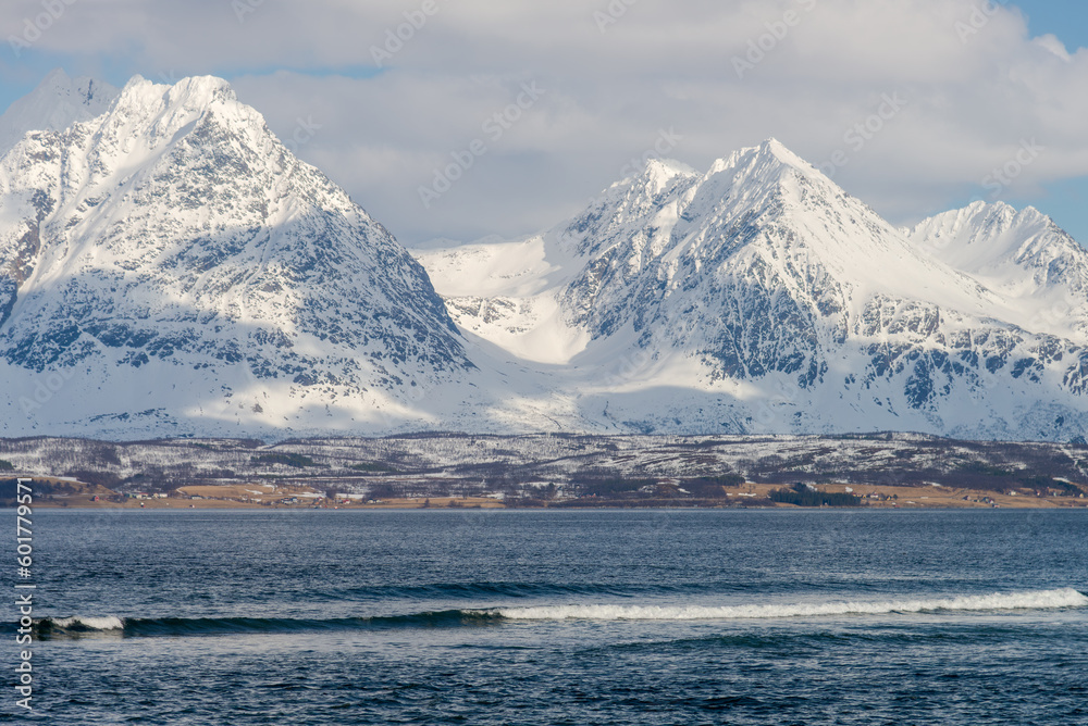 Surfing waves in front of some snowy pointy peaks