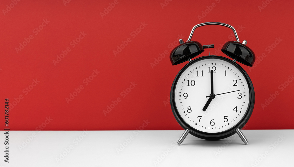 Black alarm clock on a red background Black alarm clock on a red background