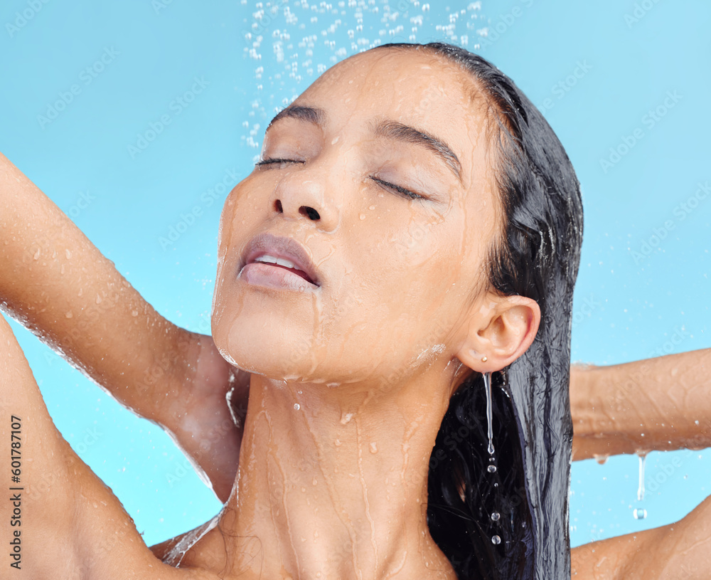Naklejka premium Shower, cleaning and woman washing hair in studio for beauty, wellness and hygiene on blue background. Haircare, skincare and female model relax in water splash, showering and cleansing isolated