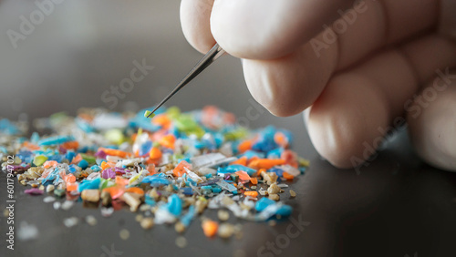 Macro shot of a person with medical gloves and tweezers inspecting a pile of micro plastics. Concept of water pollution and global warminMacro shot on a bunch of microplastics that cannot be recycled.