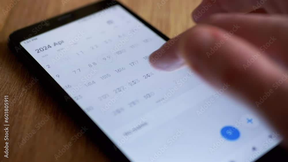 Female Finger is Scrolling Calendar App on Mobile Phone Screen Looking for Date. Close up. 2024 year, month, day, date. Search for Valentine's Day. Electronic calendar in a smartphone. Isolated.