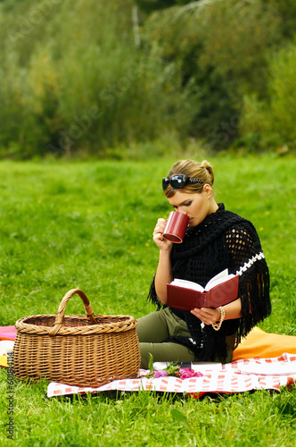 Young business woman with cup during picnic on green meadows outdoors