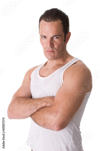 A handsome young man after working out, wearing a sleeveless shirt, standing with his arms crossed.