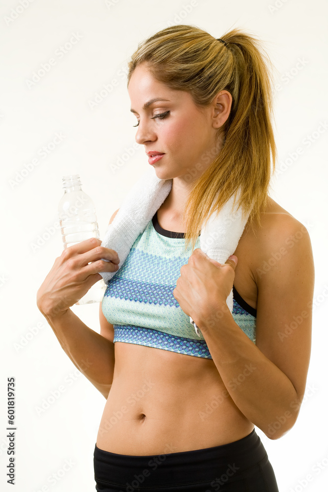Attractive blond woman in great physical shape wearing workout attire standing on white with a towel around neck Attractive blond woman in great physical shape wearing workout attire standing on white with a towel around neck