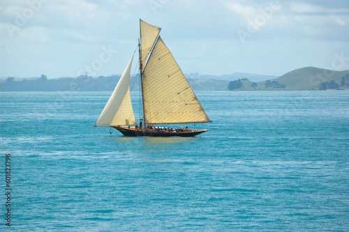 Vintage leisure sail boat with tourists on vacation cruising around islands along sea shore