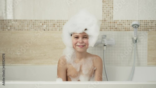 Funny boy with foam on a head dancing in the bath photo