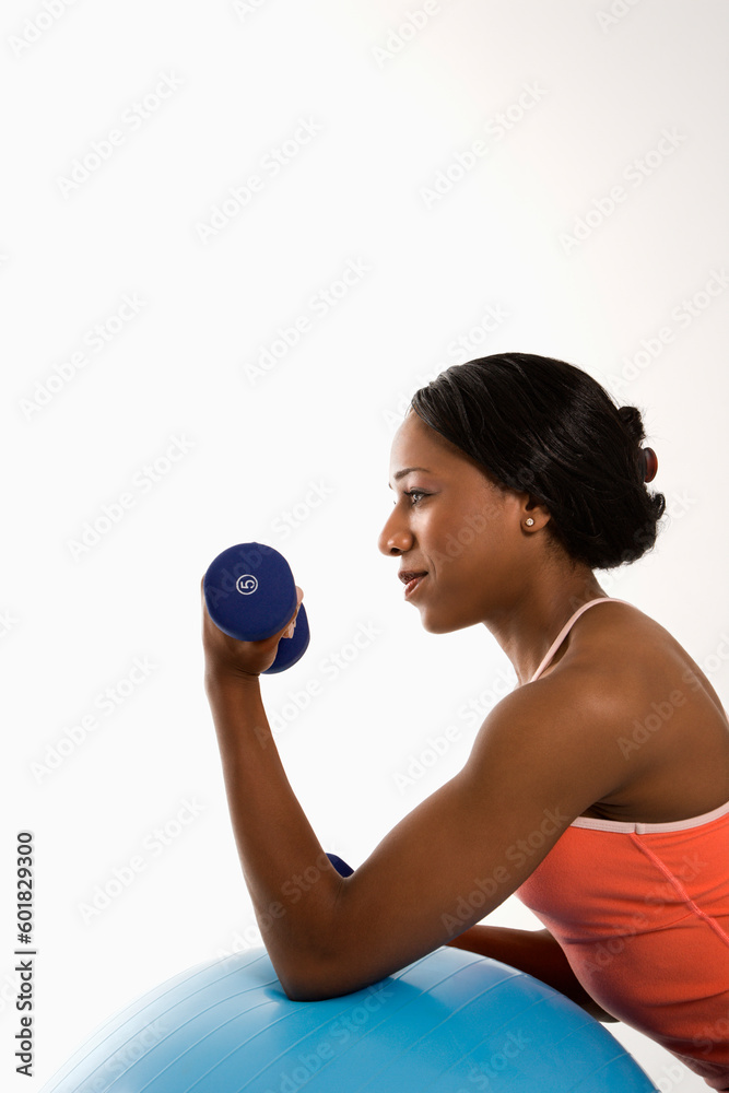 Profile of African American young adult woman leaning on exercise ball holding dumbbell. Profile of African American young adult woman leaning on exercise ball holding dumbbell.