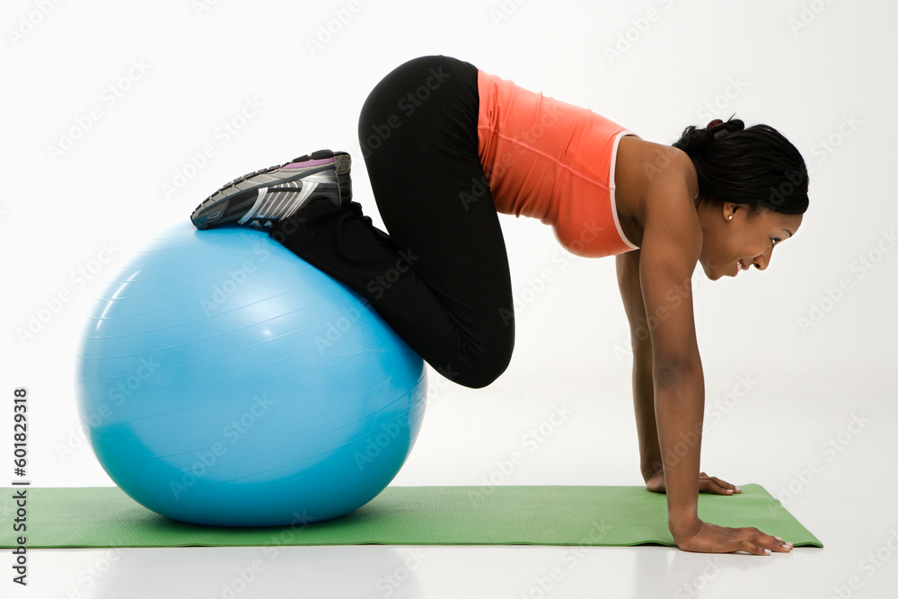 Profile of African American woman working out using an exercise ball. Profile of African American woman working out using an exercise ball.