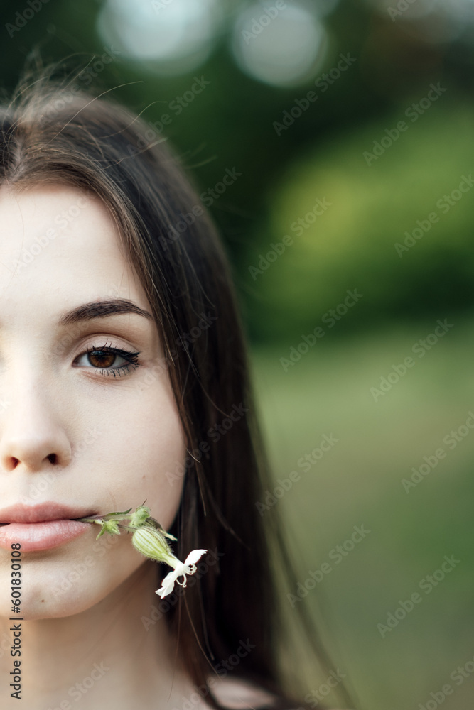 Beautiful young woman covering eye with daisy flower on nature background. Natural beauty, natural cosmetics, skin care. Beautiful young woman covering eye with daisy flower on nature background. Natural beauty, natural cosmetics, skin care.