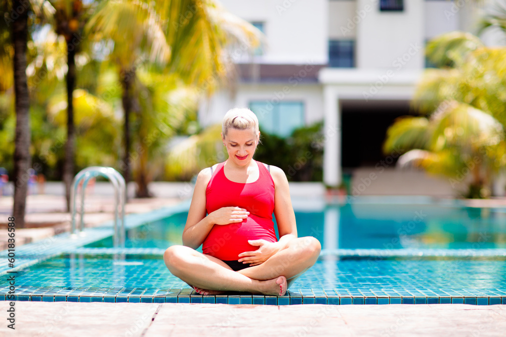Pregnant woman training in swimming pool. Yoga for mom and baby. Healthy and active pregnancy.  Sport and exercise for young expecting mom. Fitness ball exercising. Swim holiday and water fun.