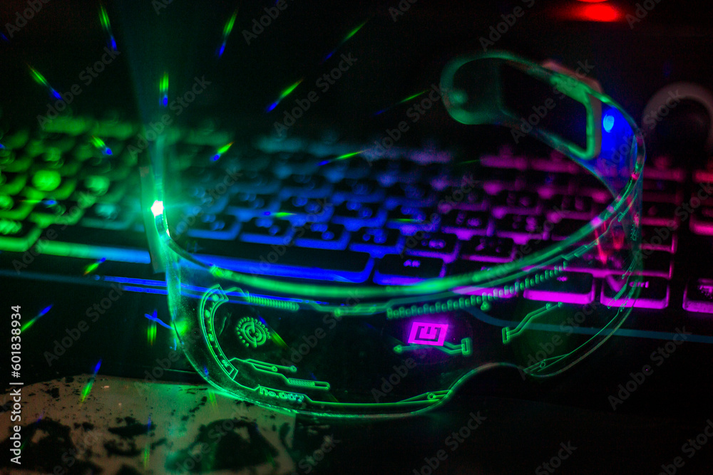 Glowing light green futuristic glasses with transparent glass lie on a multi-colored keyboard close-up
Glowing light green futuristic glasses with transparent glass lie on a multi-colored keyboard close-up