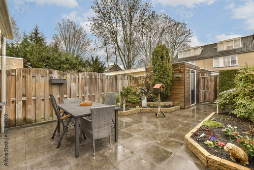 a backyard area with a table, chairs and some plants on the ground in front of a fenced back yard