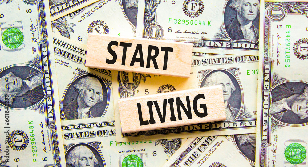 Start living symbol. Concept words Start living on beautiful wooden block. Beautiful background from dollar bills. Business and Start living concept. Copy space.