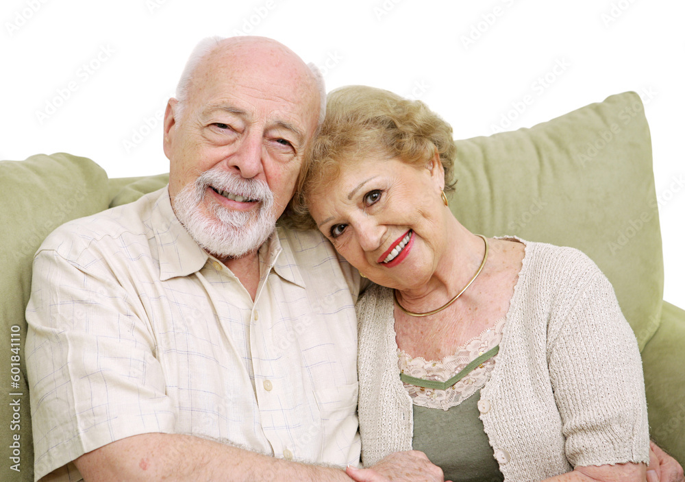 An attractive senior couple at home on the couch together. Isolated on white. An attractive senior couple at home on the couch together. Isolated on white.