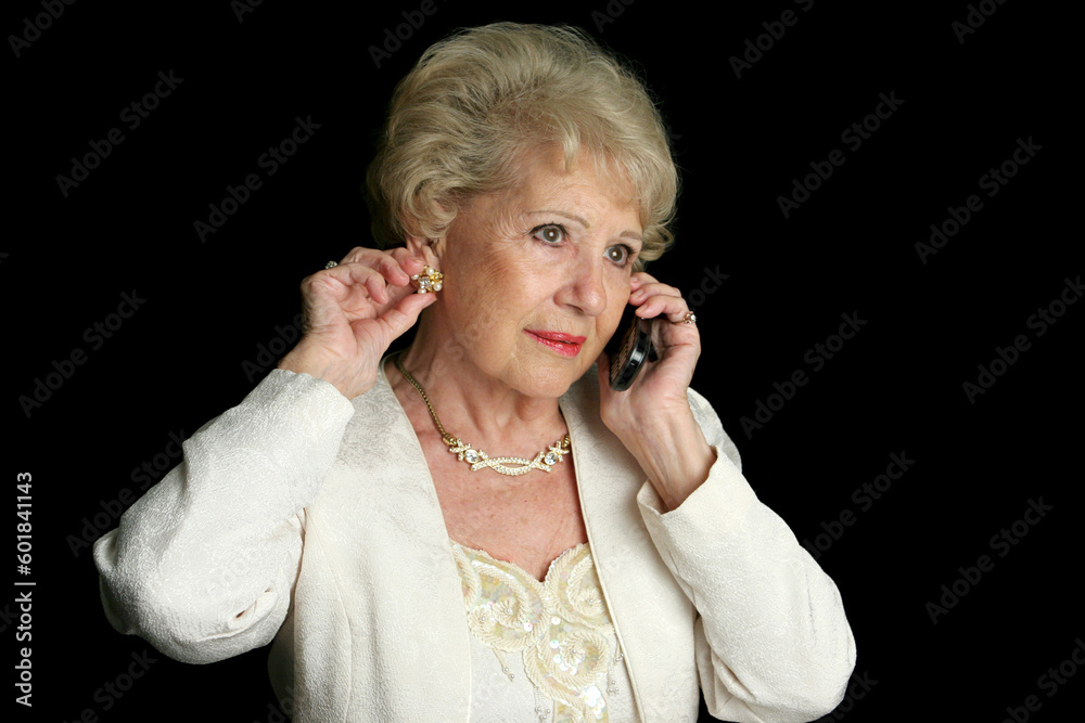 A beautiful senior lady talking on the phone and putting on her jewelry for an evening out.