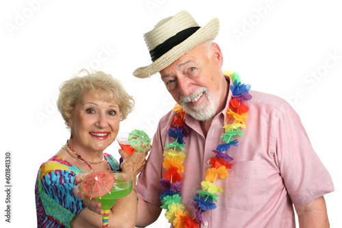 An attractive elderly couple on a tropical vacation, drinking cocktails.