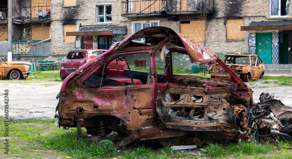 The car that burned down after the bombing of the city stands in the courtyard of a destroyed house. War between Russia and Ukraine. Fragments of a car after artillery shelling.