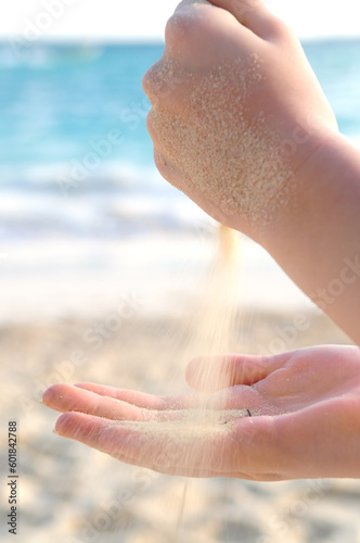 Hands pouring fine sand on a beach