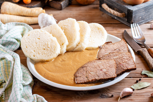 Svickova na smetane ( beef in sour cream sauce) served with knedlik (bread dumpling) on the table, traditional Czech cuisine photo