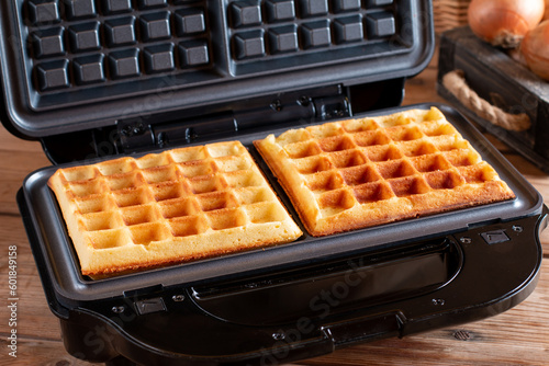 Cooking waffles stuffed with sausage, cheese. Pizza waffle, piffle. Open waffle iron. Trend of the year, popular food