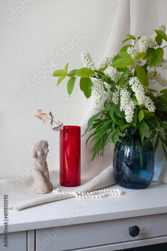 Interior decor. Flowers in a vase, clay sculpture and pearl beads in table. Selective focus