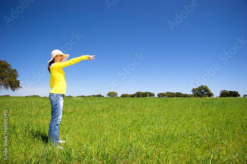 happy woman on a beautiful green meadow pointing something