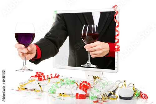 A man is offering a glass of wine from inside the computer's screen. Confetti scattered arroung the computer. photo